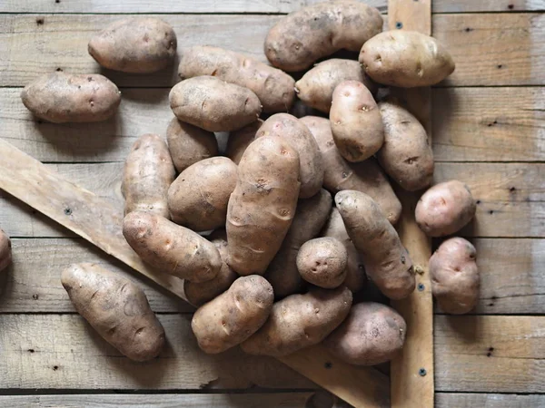 Kartoffelknollen auf einem hölzernen Hintergrund in Großaufnahme. Lagerung von Kartoffeln in einer Holzkiste. — Stockfoto