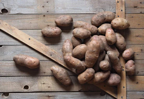 Kartoffelknollen auf einem hölzernen Hintergrund in Großaufnahme. Lagerung von Kartoffeln in einer Holzkiste. — Stockfoto