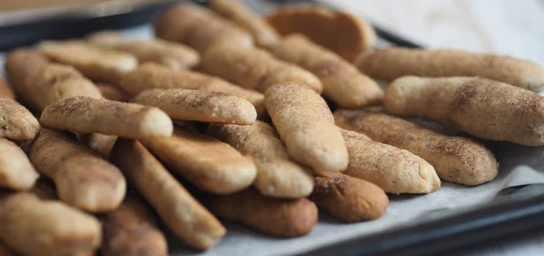 Hausgemachte Shortbread-Kekse mit Zimt und Nüssen auf einem schwarzen Backblech für den Ofen. Wir backen Plätzchen. — Stockfoto