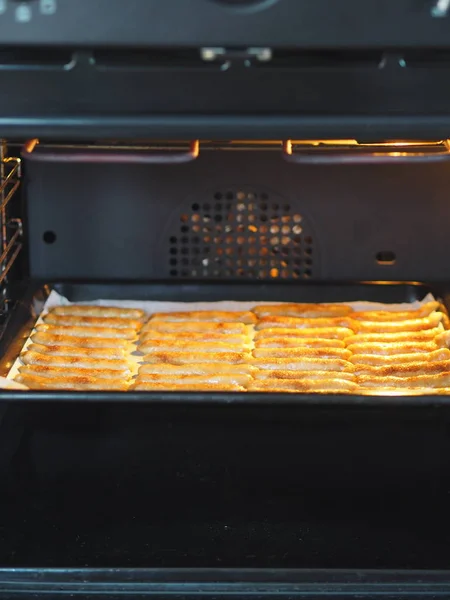 Galletas caseras de pan corto con canela y nueces en una bandeja negra para hornear para el horno. Cocinamos galletas . — Foto de Stock