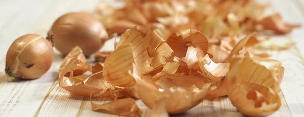 Penggunaan kulit bawang dalam pengobatan dan untuk mewarnai telur Paskah. Kulit bawang dan bawang pada latar belakang kayu. — Stok Foto