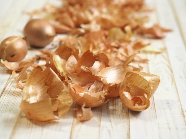 The use of onion skins in medicine and for coloring Easter eggs. Onion skin and onion on a wooden background.