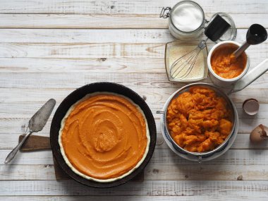 Yuvarlak ev yapımı balkabaklı turta. Yemek pişirme aşaması. Dolguyu yaydık. Ahşap arka plan. Ev yapımı pişirme..