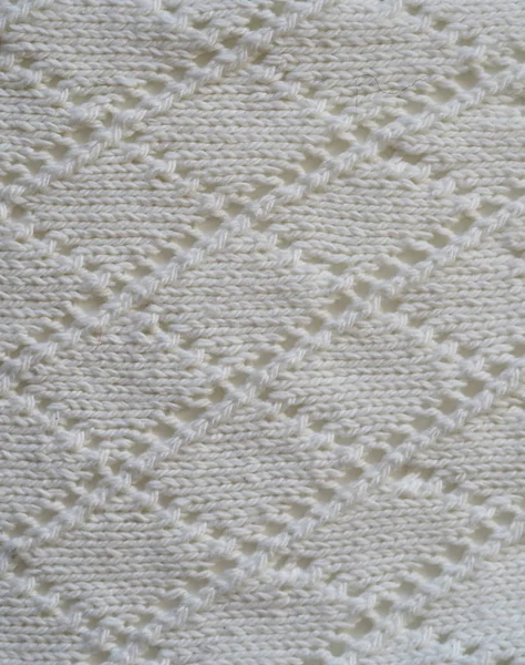 Frammento di un tessuto lavorato a maglia di lavoro a traforo manuale che lavora a maglia da filato bianco. Vista dall'alto. Verticale . — Foto Stock