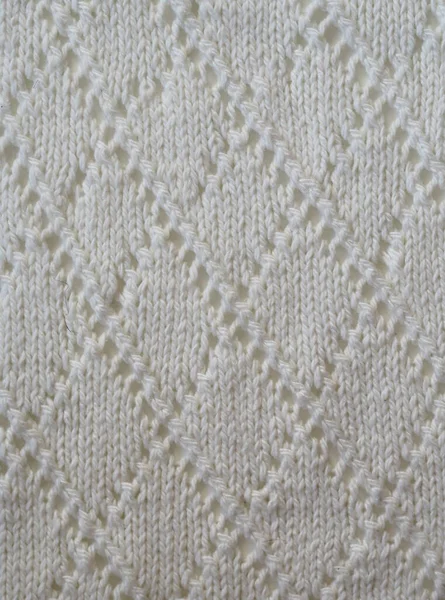 Fragment of a knitted fabric of openwork manual knitting from white yarn. View from above. Vertical. — Stock Photo, Image