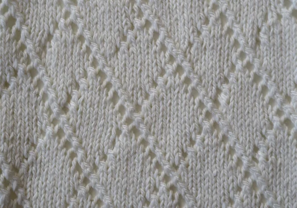 Fragment of a knitted fabric of openwork manual knitting from white yarn. View from above. Horizontal. — Stock Photo, Image