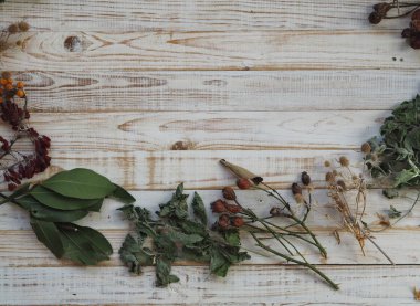 Kurutulmuş şifalı bitkiler kullanma kavramı. Farklı şifalı bitkilerle ahşap beyaz arka plan. Bitkiler ve çiçeklerle beden eğitimi..