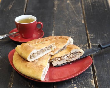 Ev yemeği. Siyah antik bir masada kırmızı tabakta lahana ve nehir balığı turtası. Evde yemek pişirmek. Küçük bir kutlama..