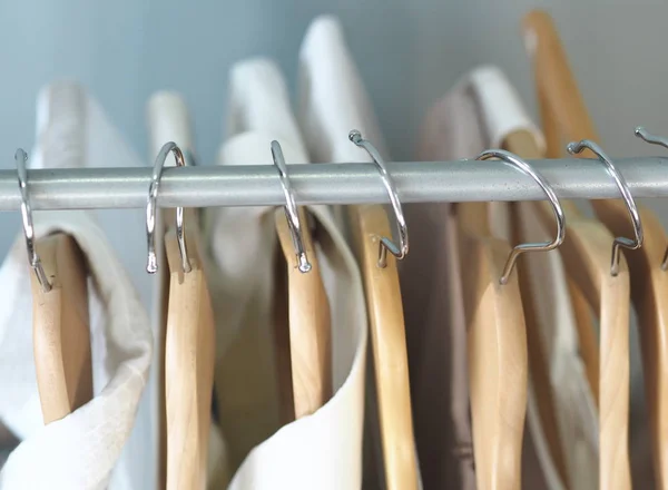 Hangers hangers met lichte mannelijke en vrouwelijke kleding. Grijze achtergrond. — Stockfoto