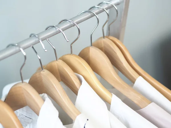 Hangers hangers met lichte mannelijke en vrouwelijke kleding. Grijze achtergrond. — Stockfoto