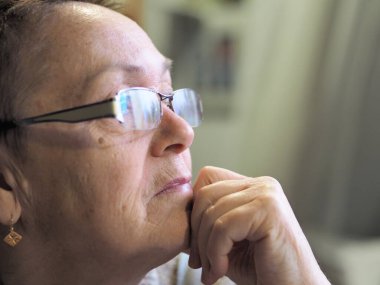 İyi bir görüş için gözlüklü yaşlı bir kadının yakın çekimi. Geçmişi ve geleceği düşünür..