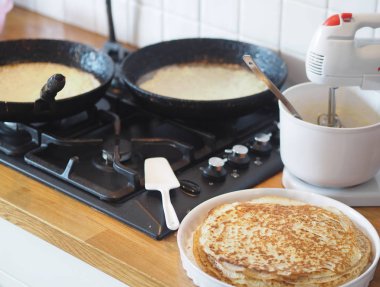 Spring, we meet Maslenitsa. Seeing off winter. Cooking pancakes on a gas stove. Next to the dough and ready-made pancakes.