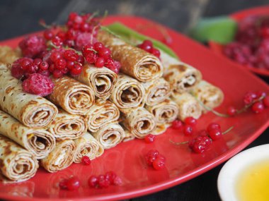 Pancakes with berries and sour cream for traditional winter Slavic holiday Maslenitsa or russian pancake week. Jam, honey on table