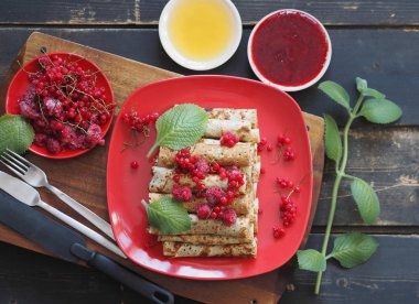 Pancakes with berries and sour cream for traditional winter Slavic holiday Maslenitsa or russian pancake week. Jam, honey on table