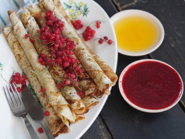 Pancakes with berries and sour cream for traditional winter Slavic holiday Maslenitsa or russian pancake week. Jam, honey on table