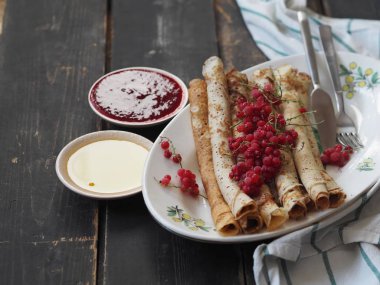 Pancakes with berries and sour cream for traditional winter Slavic holiday Maslenitsa or russian pancake week. Jam, honey on table