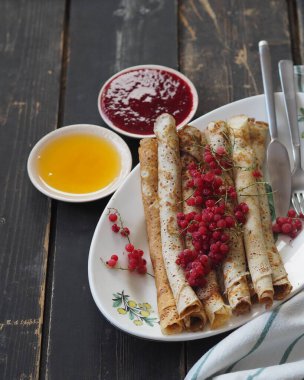 Pancakes with berries and sour cream for traditional winter Slavic holiday Maslenitsa or russian pancake week. Jam, honey on table