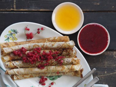 Pancakes with berries and sour cream for traditional winter Slavic holiday Maslenitsa or russian pancake week. Jam, honey on table