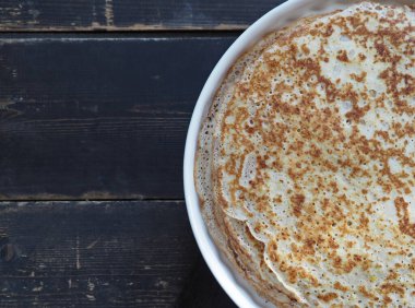 Spring, we meet Maslenitsa. Seeing off winter. Cooking pancakes on a gas stove. Next to the dough and ready-made pancakes.