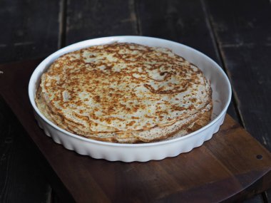 Maslenitsa. Hot pancakes laid on a plate. Festive background with artificial lighting. Selective focus. Place for text.