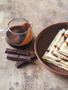 Krepler Shrovetide 'e çikolatalı krema döktü. Tahta kahverengi bir zemin üzerinde. Çikolata kremalı cam vazo ile. Mesaj için yer. Kahverengi ahşap arka plan.