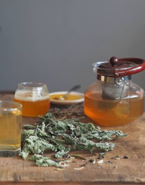 Bitkisel ilaçlar. Yeşil bitki çayının sağlık yararları kavramı. Çaydanlık ve fincanlar martılar ve tıbbi malzemelerle ahşap kahverengi bir masada.