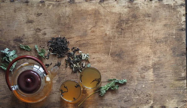 Medicina herbácea. O conceito dos benefícios para a saúde do chá de ervas verdes. Bule e xícaras em uma mesa marrom de madeira com gaivotas e medicinais — Fotografia de Stock