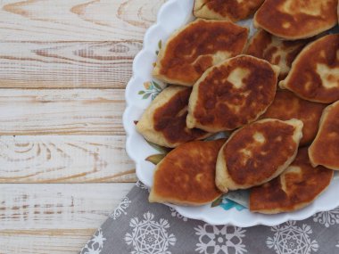 Farklı dolgulu ev yapımı küçük pastalar, et, yumurtalı soğan, beyaz ahşap bir masada büyük bir tabakta lahana. Yukarıdan bak..