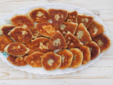 Farklı dolgulu ev yapımı küçük pastalar, et, yumurtalı soğan, beyaz ahşap bir masada büyük bir tabakta lahana. Yukarıdan bak..