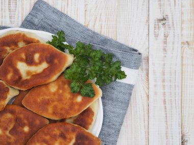 Farklı dolgulu ev yapımı küçük pastalar, et, yumurtalı soğan, beyaz ahşap bir masada büyük bir tabakta lahana. Yukarıdan bak..