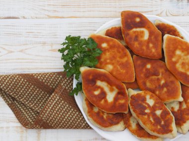 Farklı dolgulu ev yapımı küçük pastalar, et, yumurtalı soğan, beyaz ahşap bir masada büyük bir tabakta lahana. Yukarıdan bak..