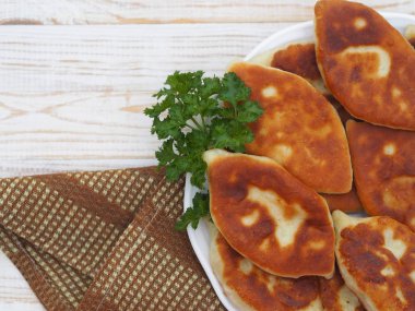 Farklı dolgulu ev yapımı küçük pastalar, et, yumurtalı soğan, beyaz ahşap bir masada büyük bir tabakta lahana. Yukarıdan bak..