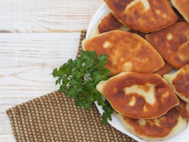 Farklı dolgulu ev yapımı küçük pastalar, et, yumurtalı soğan, beyaz ahşap bir masada büyük bir tabakta lahana. Yukarıdan bak..