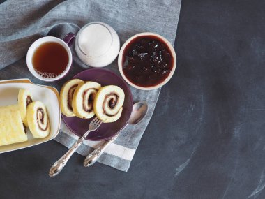 Ev yapımı bisküvi rulosu, tatlı erik reçeli ve koyu arka planda çay. Doğal ev yapımı tatlı. Üst Manzara. Metin için yer.