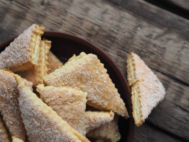 Ahşap bir arka planda kahverengi bir tabakta ev yapımı kurabiye puf böreği üçgeni. Üst Manzara. Mesaj için yer. Tatil için hazırlık.