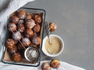 Gri bir kırsal arka planda, cam fırında pişirilmiş donutlar ve krema şekerli süzgeç..
