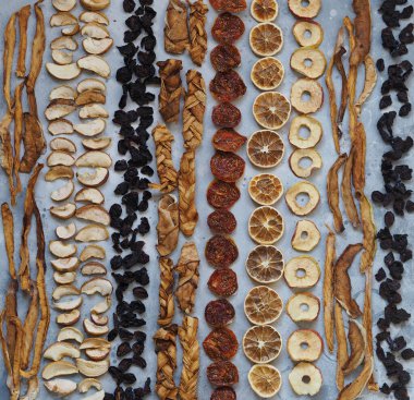 Kurutulmuş meyvenin faydaları. Ahşap bir arka planda kurumuş meyve cipslerinin arkaplanı, tahta gri bir masanın üzerine dizilmiş. Ev yemeği. Doğal sağlıklı ürün..