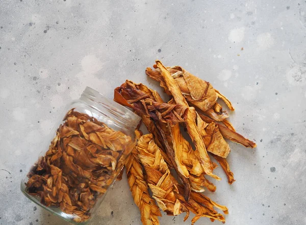 Dried melon chips in a glass jar on a wooden background. Home cooking. Natural healthy product. Place for text. Top view.