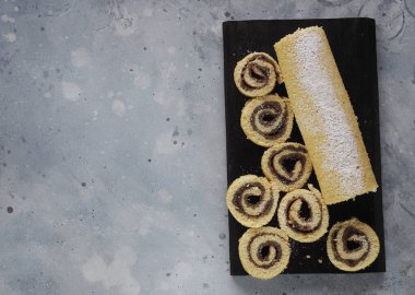 Ev yapımı erik reçeli, pudra şekeri serpiştirilmiş gri ahşap zemin üzerinde koyu renk bir mutfak tahtası. Mesaj için yer var..