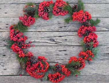 Noel ya da yeni yıl arkaplanı. Ahşap arka planda yeşil ladin dalları ve kırmızı Rowan çelengi. Yazı için yer