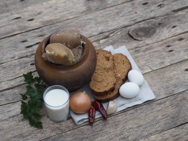 Haşlanmış patatesin sağlık yararları. Doğal basit piknik ürünleriyle birlikte doğal ahşap bir arka planda, kilden bir tencerede patates..