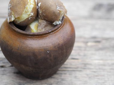 Patatesin sağlığa faydası. Doğal ahşap arka planda, kilden bir tencerede haşlanmış patates..