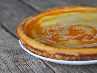 Balkabağından yapılmış nefis ev yapımı peynirli kek, çırpılmış yumurtaların üzerine şeker dökülmüş, ahşap arka planda, yan manzaralı. Yazı için yer var..