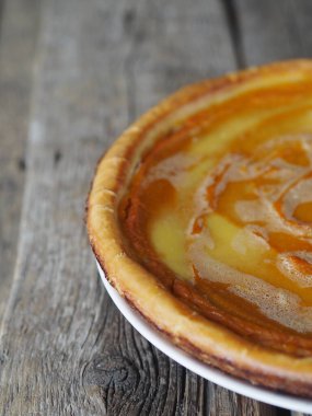 Balkabağından yapılmış nefis ev yapımı peynirli kek, çırpılmış yumurtaların üzerine şeker dökülmüş, ahşap arka planda, yan manzaralı. Yazı için yer var..