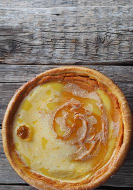 Ev yapımı fırınlanmış peynirli kek, balkabağından yapılmış, çırpılmış yumurtaların üzerine şeker dökülmüş, ahşap bir arka planda. Yakın plan, üst görüş. Mesaj için yer..