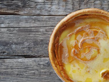 Ev yapımı fırınlanmış peynirli kek, balkabağından yapılmış, çırpılmış yumurtaların üzerine şeker dökülmüş, ahşap bir arka planda. Yakın plan, üst görüş. Mesaj için yer..