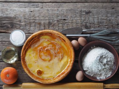 Ev yapımı kekler ve mutfak malzemeleriyle yemek pişirmek. Balkabağından turtalı kek, çırpılmış yumurtanın üstüne de tahta zemine şeker dökülmüş. Mesaj için yer var..