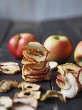 Kırsal ahşap masa üzerinde taze elmalı ev yapımı elma cipsi. Kurutulmuş meyvenin faydaları..
