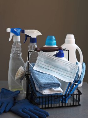 Coronavirus. Karantina sırasında evi temizleme fikri. Temizlik ürünleri ve temizlik aletleri için tıbbi koruyucu maske. Evin faydalarıyla birlikte evde vakit geçir. Yan görünüm.