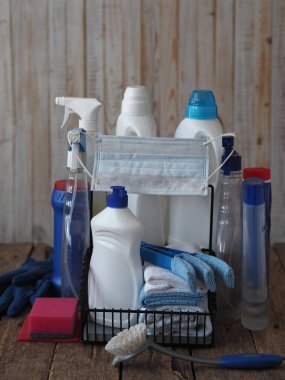 Dezenfeksiyon ve koronavirüs enfeksiyonuna karşı koruma. Ahşap bir arka planda temizlik maddesi dezenfektanından çıkan plastik şişelere takılan tıbbi bir maske. En iyi karantina seansı temizlik ve temizliktir.